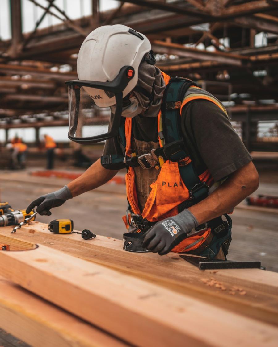 Construction worker measuring lumber on site